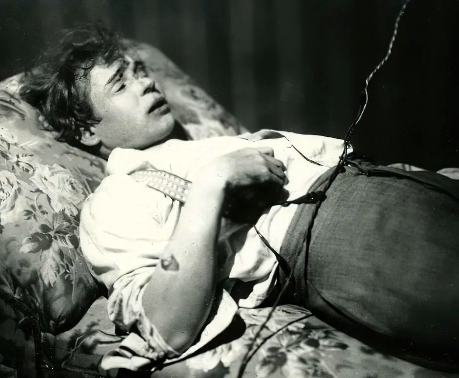 Sort-hvidt fotografi af den døde Sergej Jesenin, der ligger på en blomstret sofa i sit værelse på Hotel d'Angleterre i Leningrad, december 1925
